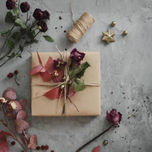 A gift wrapped with dried flowers on a gray surface.