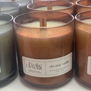 Close-up of a trio of scented candles in glass jars with wooden wicks.